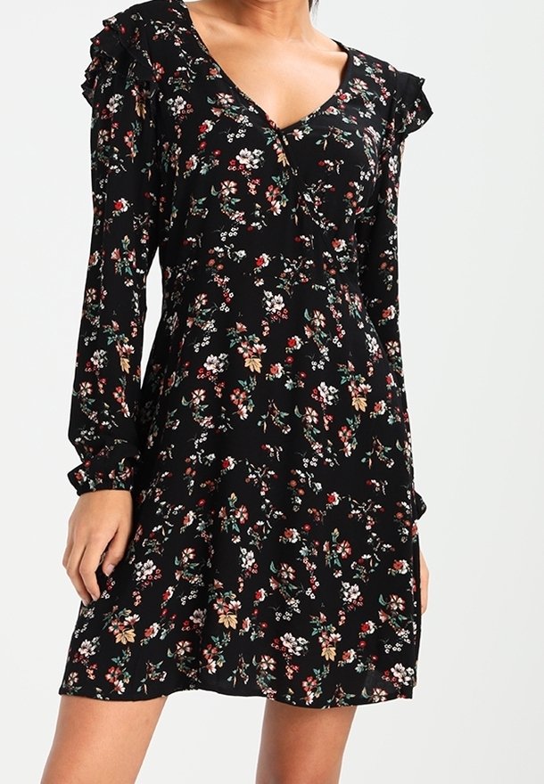 Robe noire à manches longues avec des accents froncés, arborant un motif floral en rouge, blanc et vert. Un décolleté en V complète le design.