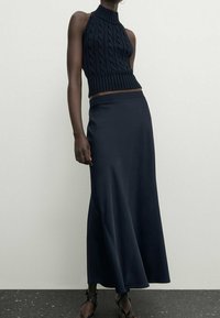 Haut court en tricot bleu marine avec col monté et motif en gros grains, associé à une longue jupe lisse bleu marine foncé, dotée d'un ourlet évasé.