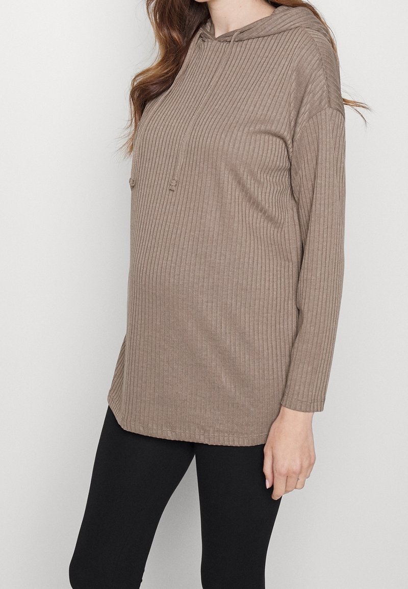 Felpa marrone a coste con maniche lunghe, tasca frontale e cordini regolabili. L'orlo è leggermente più lungo ai lati per garantire maggiore comfort.