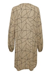 Tunique beige avec un motif géométrique de feuilles noires, manches longues avec poignets élastiques, coupe ample et encolure ronde. Pas de fermetures visibles.