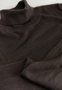 Brown turtleneck sweater with a soft, knitted texture. Features a high neck and overlapping panels in the body for a layered design.