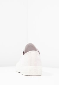 Baskets en daim rose clair avec un design bas. Semelle en caoutchouc blanche et languette arrière avec le logo "Converse All Star" embossé. Détail de couture simple.