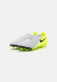 Botas de fútbol con un upper sintético de color gris claro, suela negra y acentos en amarillo neón. Presenta un diseño texturizado y cierre con cordones.