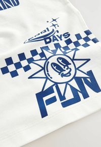 Weißes Baumwoll-T-Shirt mit blauen grafischen Elementen, darunter eine lächelnde Sonne, der Text "FUN", ein kariertes Muster und dekorative Funkelnde.