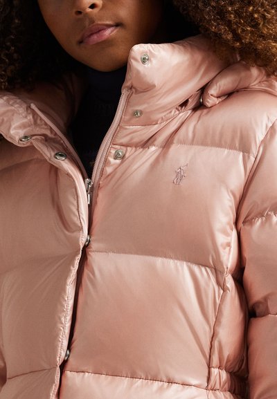 Casaco puffer rosa claro feito de material brilhante com fecho de zíper e botão de pressão. Possui um pequeno logótipo bordado no peito e um design acolchoado.