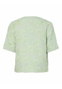 Lys grønn teksturert kortermet topp med blomsterdesign, med en litt løs passform og rund halslinning. Bakre visning vist.
