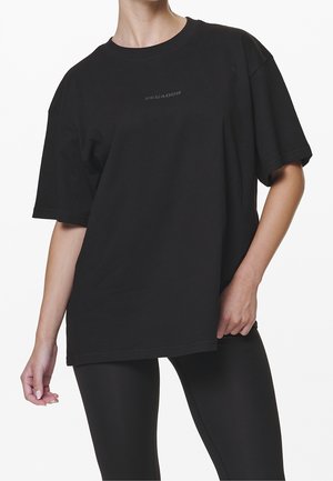 Black cotton t-shirt with a relaxed fit, short sleeves, crew neckline, and “PEGADOR” logo in a contrasting dark gray. Smooth texture.