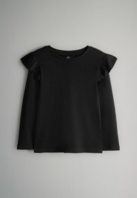 Svart långärmad topp med volangdetaljer på axlarna, rund halsringning och en mjuk bomullstextur. Perfekt för lager-på-lager eller som casual outfit.