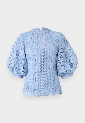 Hele helesinine pitsbluus, millel on keerukad lillemustrid, puffse varrukad, lainelised ääred ja keskel vertikaalne kujunduse detail.