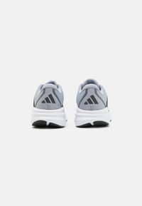 Gray athletic shoes with black accents, mesh upper, padded collar, and white sole featuring textured grip pattern. Three-stripe logo visible.