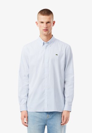 Camisa de manga larga a rayas en azul claro y blanco, con cuello abotonado y pequeño logo verde en el pecho. Tejido de algodón.