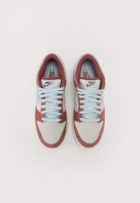 Ténis Nike com um cabedal de malha azul claro, detalhes em camurça bordô, atacadores planos azul claro e uma sola de borracha creme.