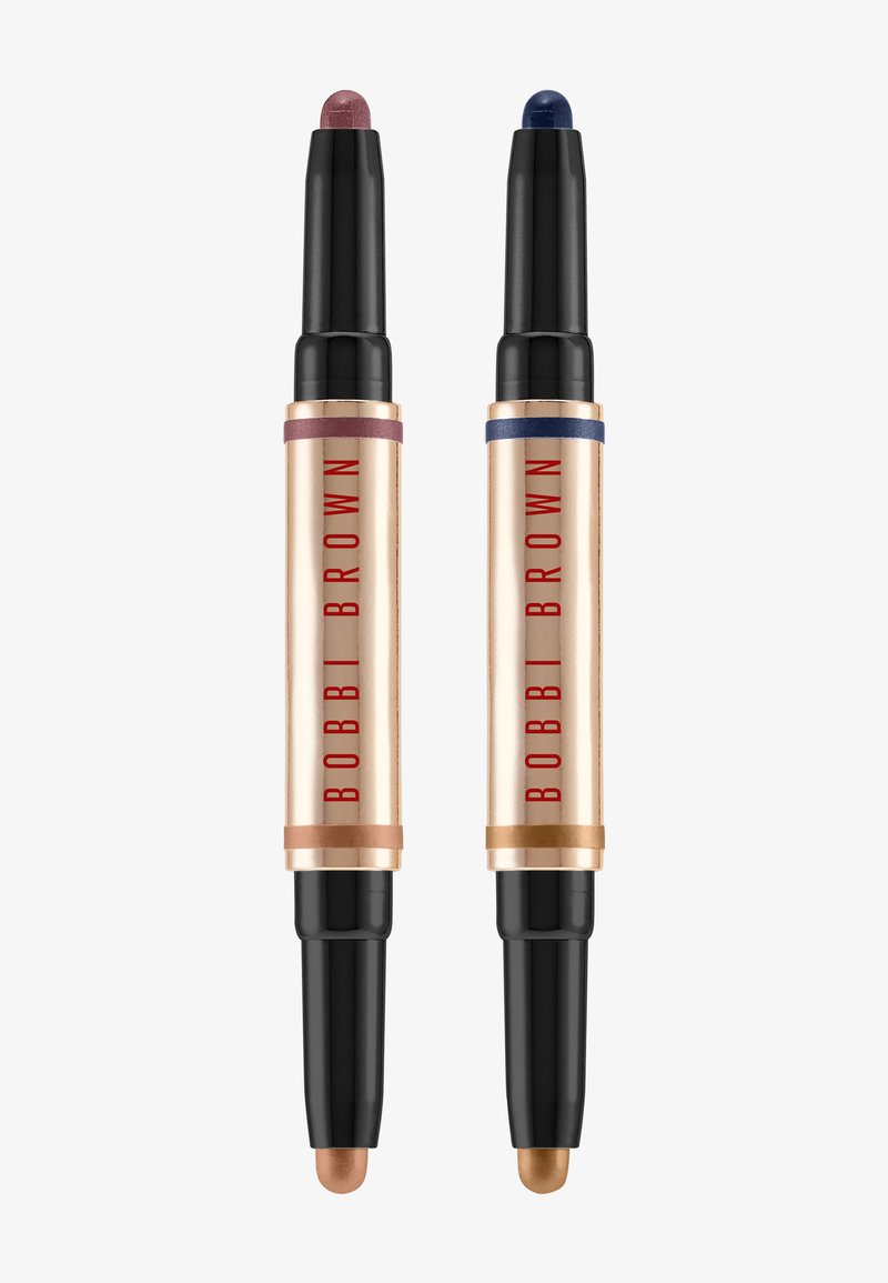 To Bobbi Brown øjenskygger med dobbeltsidet stift og sorte låg; den ene med nuancer af pink og bronze, den anden med navyblå og guldfarvede nuancer.