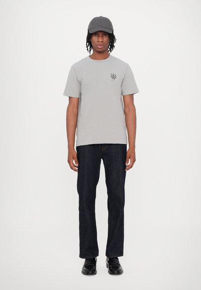 Gray cotton t-shirt with short sleeves and a logo on the left chest, paired with dark blue straight-leg jeans and black shoes.