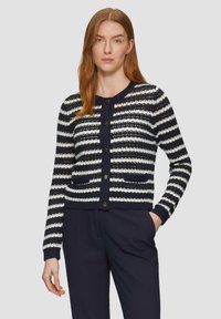Cardigan a righe blu navy e bianche con collo rotondo, bottoni frontali e due tasche. Texture lavorata a maglia, maniche lunghe, design aderente.