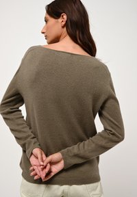 Maglione a maniche lunghe verde oliva con vestibilità comoda, scollatura ampia e tessuto morbido e testurizzato. La vista posteriore mostra cuciture minime e polsini.