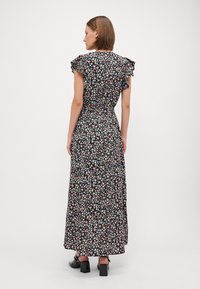 Robe maxi florale noire. Dotée de manches courtes à volants, d'une taille cintrée et d'une jupe fluide ornée de petits motifs floraux roses, bleus et blancs.