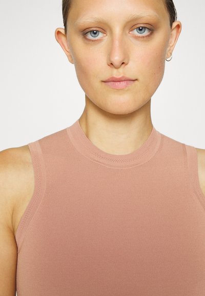 Ροζ χωρίς μανίκια τοπ, φτιαγμένο από ριμπ ύφασμα, με ψηλό λαιμό και χωρίς ραφές για ομαλή φινίρισμα.