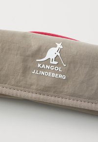 Kangol and J.Lindeberg branded accessory in a beige fabric with a smooth texture, featuring a white kangaroo logo and a red zipper.