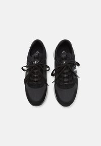 Svarta sportskor med en kombination av matta och strukturerade material, runda tår och platta skosnören med en logotyp på sidan.