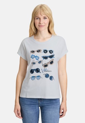 T-shirt gris clair à manches courtes avec un imprimé graphique de diverses lunettes de soleil dans des tons de bleu et de marron, avec différentes formes et designs.