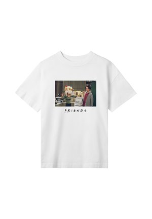 T-shirt bianco con una scena di sitcom televisiva che mostra una donna con un tacchino in testa e un uomo che guarda, con la didascalia "FRIENDS" sotto.