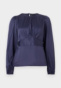 Tamno plava majica dugih rukava s okruglim izrezom, sakupljenim prednjim dijelom i elastičnim manžetama. Izrađena od glatkog, laganog materijala s uskim krojem.