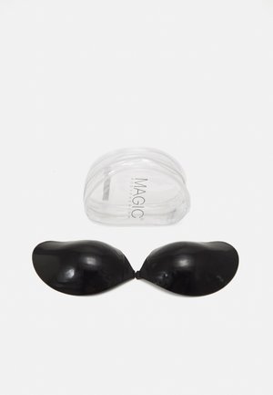 Black adhesive silicone cups shaped like half globes, connected at the center, placed next to a transparent storage case labeled "MAGIC."