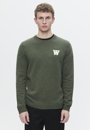 Olive green sweater with a crew neckline and ribbed cuffs, featuring a white 'W' logo on the chest, made from a textured knit fabric.