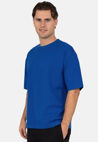 T-shirt bleu royal à manches courtes avec un col rond, fabriqué en tissu de coton doux. La coupe est décontractée et la texture est lisse.