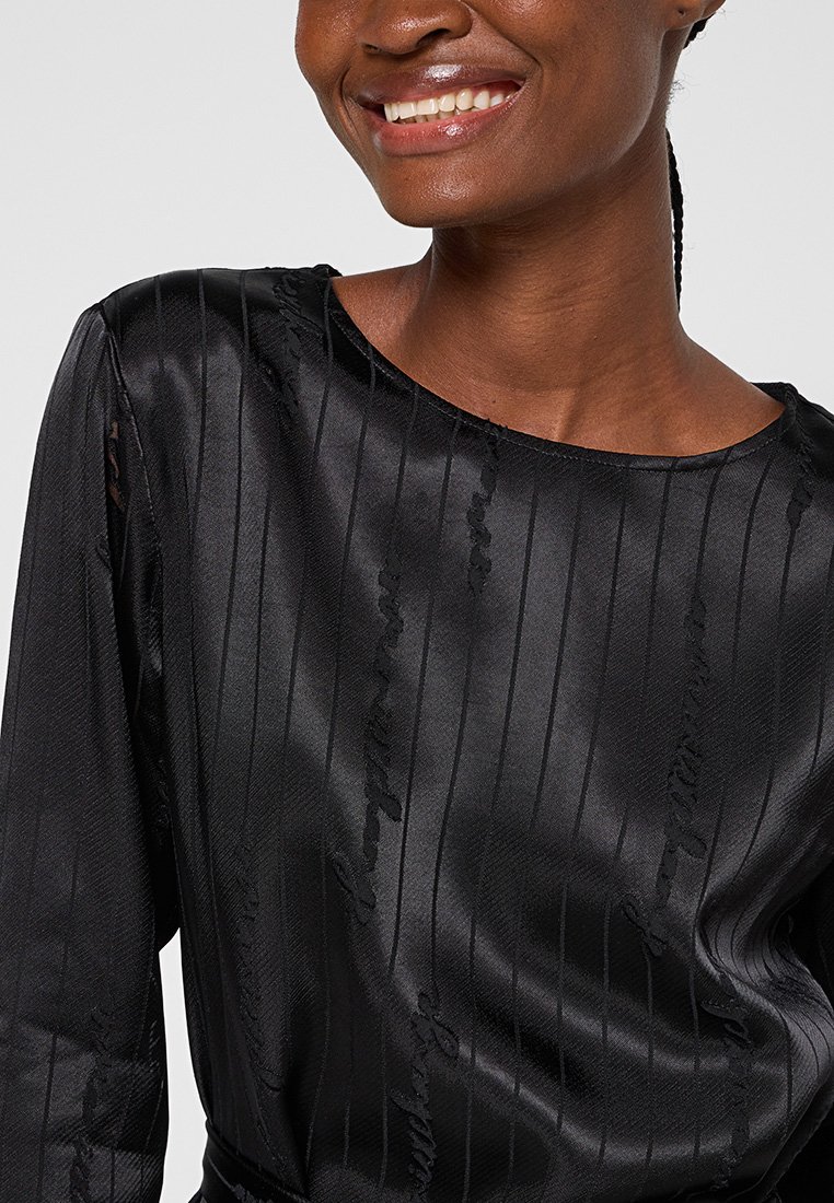 Černé saténové šaty s vertikálními pruhy a jemným textovým vzorem. Kulatý výstřih a dlouhé rukávy, hladká textura, elegantní splývání.