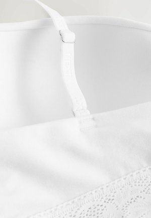 Vit bh med slät tyg, justerbar rem med silverdetaljer och spetskant längs bandet. Mjuk textur och sömlös design.