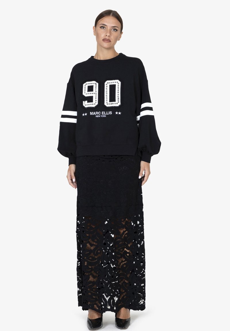 Felpa nera con grafica "90" e "Marc Ellis New York", abbinata a una gonna di pizzo nera con disegni intricati e silhouette dritta.