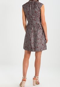 Bezramínkový šaty s květinovým vzorem v odstínech šedé a burgundské, se staženým pasem a zipem na zádech. Vystavené s béžovými sandály na blokovém podpatku.