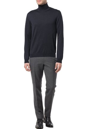 Marineblauwe coltrui van een lichtgewicht breiwerk, gecombineerd met op maat gemaakte donkergrijze broeken. Opvallende accenten zijn onder andere het aansluitende ontwerp en de geribde manchetten.