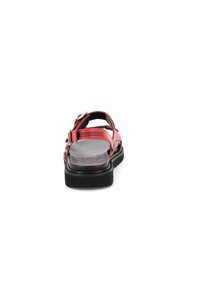 Sandales rouges au design épuré, dotées de sangles réglables, d'une semelle intérieure texturée et d'une semelle noire épaisse, vues de l'arrière.