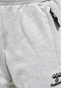 Graue Baumwoll-Sweatpants mit strukturiertem Finish, elastischem Bund, seitlichen Taschen und einer schwarzen Reißverschlusstasche mit Logo-Design.