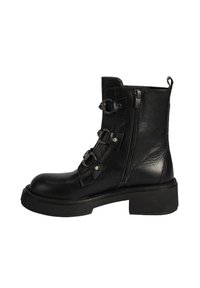 Bottine en cuir noir avec plusieurs brides décoratives, fermeture éclair latérale, semelle épaisse et finition texturée. Présente des accents de quincaillerie en ton argenté.