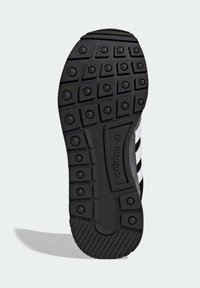 Μαύρη σόλα παπουτσιού από καουτσούκ με υφή στο πέλμα που διαθέτει κυκλικό και εξαγωνικό σχέδιο· τμήμα με λογότυπο και ανάγλυφες λεπτομέρειες.