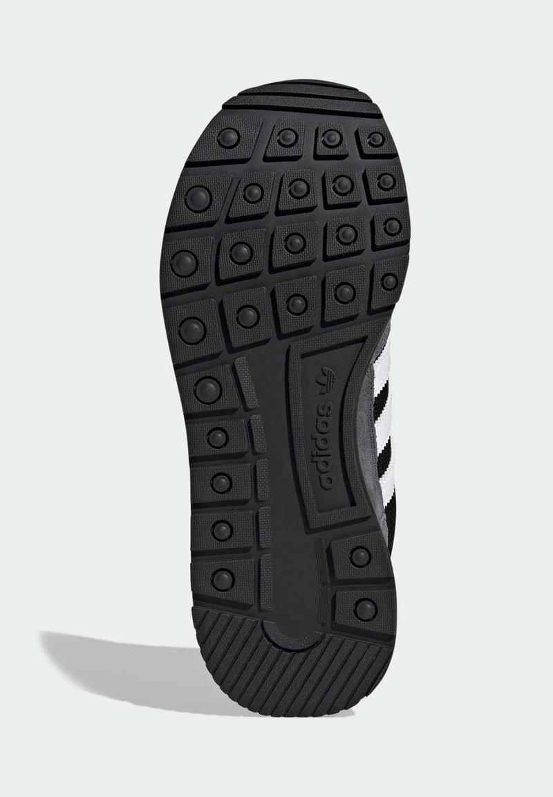 Suola di scarpa in gomma nera con motivo battistrada testurizzato a disegni circolari e esagonali; sezione marchiata con dettagli rigati.