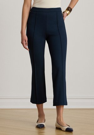 Tmavomodré krátke nohavice z elastickej látky, s prednými záhybmi a vysokým pásom. Nosia sa s dvojfarebnými balerínkami.