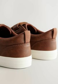 Braune Sneakers aus Kunstleder mit strukturierter Oberfläche, weißen Gummisohlen und einem gepolsterten Kragen mit einer Zuglasche an der Rückseite.