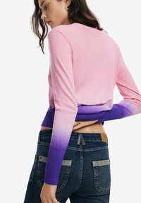 Roosa-lillas ombre lõngasviit, millel on pikad varrukad ja soonikmanused, koos tumedat tooni teksadega, millel on tagataskud.