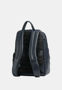 Zaino in pelle blu navy con spallacci in rete nera imbottita, design strutturato e una tasca esterna con zip. Texture liscia con hardware minimale.