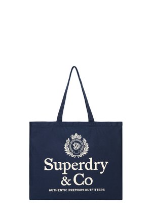 Granatowa torba typu tote z długimi uchwytami, z białym napisem ""Superdry & Co Authentic Premium Outfitters"" i logo z wieńcem laurowym.