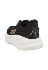 Hoka Bondi 9 joggesko har en svart mesh-overdel, hvit polstret såle, og gulllogo accenter på hælen og siden for kontrast.