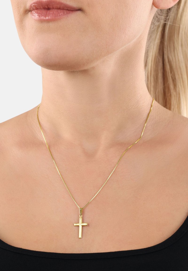 Collana con croce in oro su una sottile catena; presenta una finitura lucida con un design di croce semplice e geometrico. Lo sfondo è neutro.
