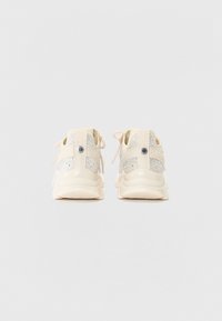 Kremfargede sneakers med et teksturert tekstiloverside, sølvglitrende detaljer og en polstret såle. Har justerbare lisser og et logodetalj.