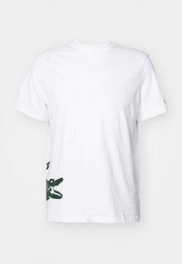White short-sleeve crew neck t-shirt with a partial dark green crocodile graphic on the lower left side.