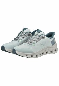 Scarpe sportive grigio chiaro con una tomaia in mesh, dettagli verde scuro e suola testurizzata con fori rotondi per un'ammortizzazione ottimale.